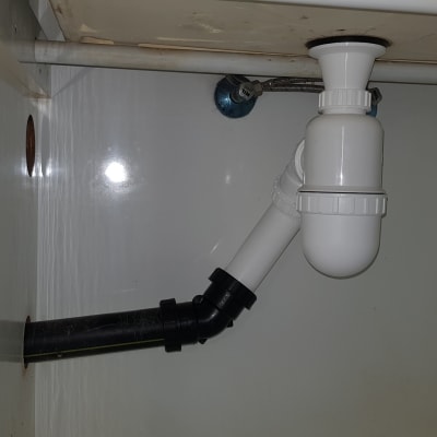 צנרת פלסטיק לבנה ושחורה מתחת לכיור