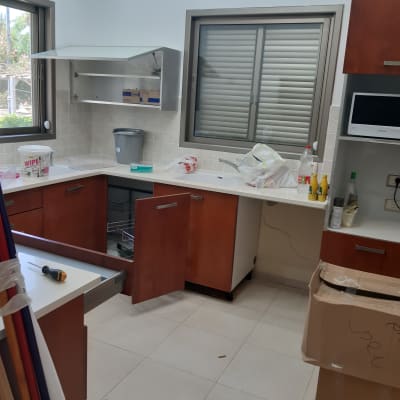 מטבח עם ארונות פתוחים, קרטון וכלי ניקוי