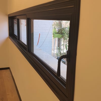 חלון אלומיניום עם מסגרת כהה וקיר לבן