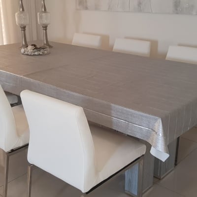 שולחן מכוסה במפה אפורה עם כיסאות מרופדים לבנים