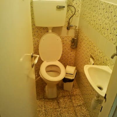 שירותים עם אסלה, כיור קטן, אריחים ישנים על הקירות