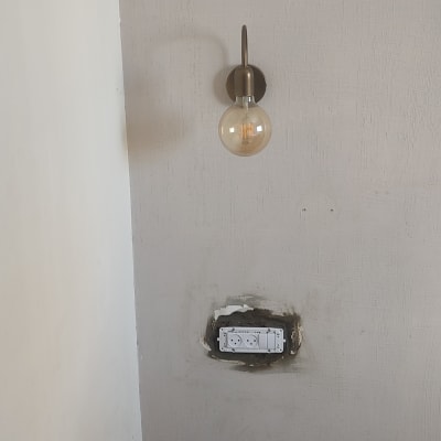 שקע חשמל בקיר עם מנורת קיר מעל