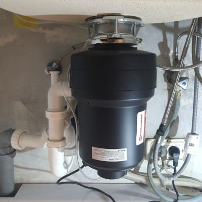 מתקן טוחן אשפה מתחת לכיור עם צינורות חיבור