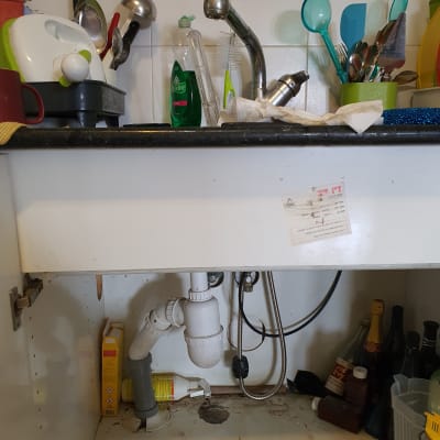 כיור מטבח עם צנרת מתחת, בקבוקי חומרי ניקוי