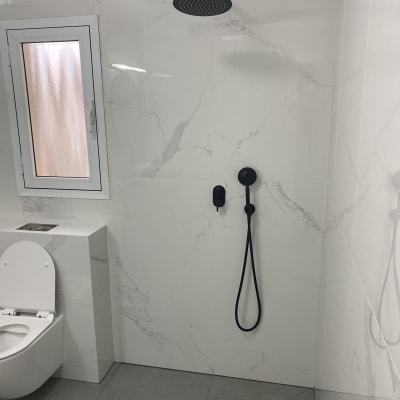 מקלחת עם ראש גשם שחור וקיר שיש לבן