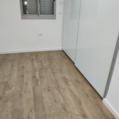 רצפת פרקט עץ בחדר ריק עם קירות לבנים