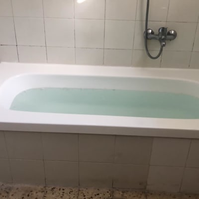 אמבטיה לבנה עם מים, אריחים לבנים על הקיר