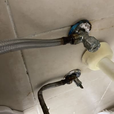 צינורות מים וברזים מתכתיים על קיר קרמיקה