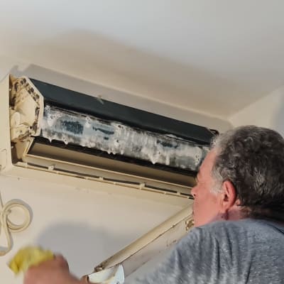 אדם מנקה מזגן עם ספוג צהוב