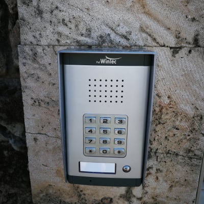 אינטרקום מתכת עם לוח מקשים על קיר אבן