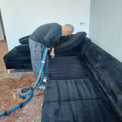 אדם מנקה ספה עם שואב אבק תעשייתי