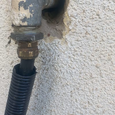 צינור מתכת מחובר לקיר עם חיבור פלסטיק