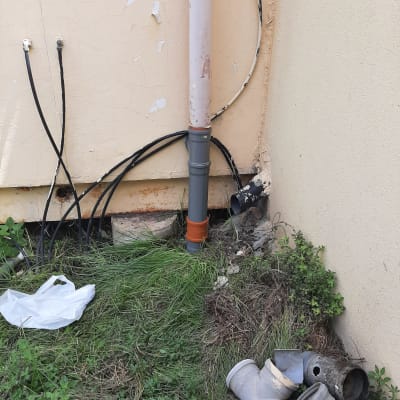 צינור ביוב מחובר לקיר עם צינורות נוספים על הקרקע