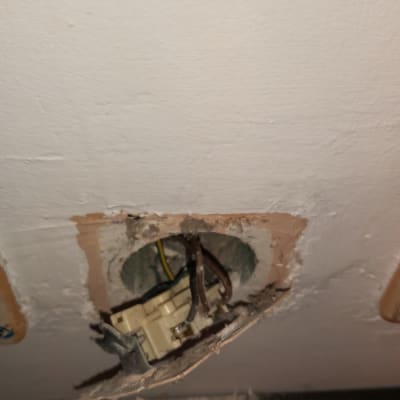 חוטי חשמל חשופים בקיר עם שקע פתוח