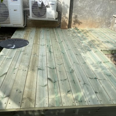 דק עץ חדש עם פתח עגול ליד מזגנים