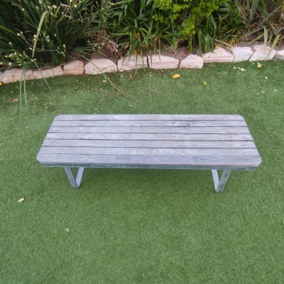 ספסל עץ על דשא מלאכותי בגינה