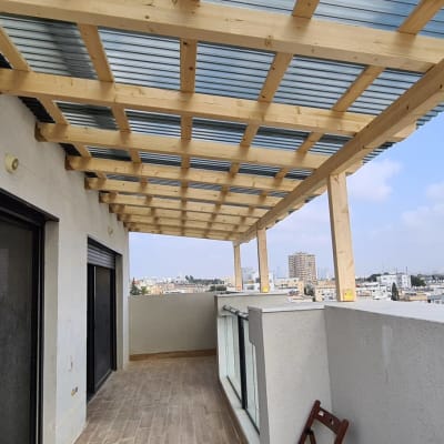 פרגולה מעץ עם גג מתכת במרפסת