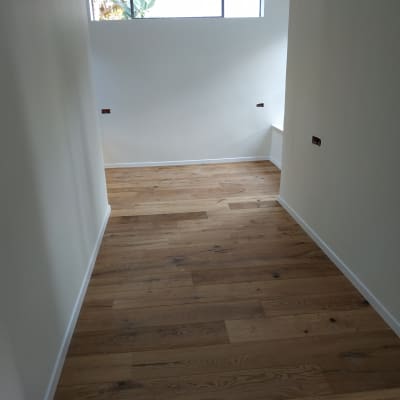 רצפת פרקט עץ בחדר מואר עם קירות לבנים