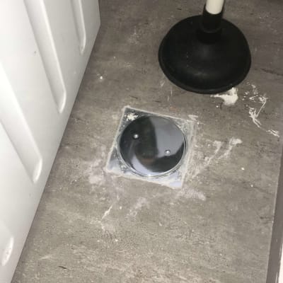 פומפה שחורה על רצפה ליד מכסה ניקוז מתכת