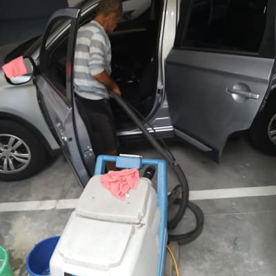 אדם מנקה רכב עם שואב אבק תעשייתי
