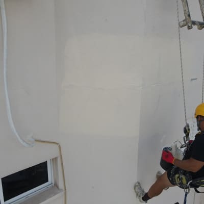 אדם עם קסדה צובע קיר חיצוני