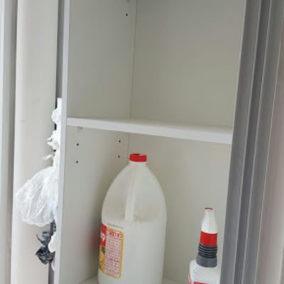 בקבוקי דבק על מדף בארון פתוח