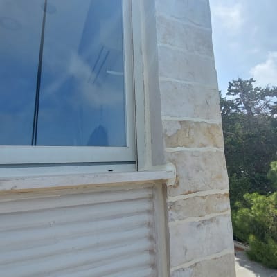 חלון זכוכית עם תריס סגור על קיר אבן