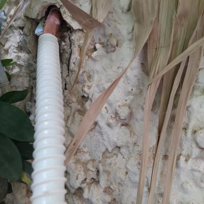 צינור פלסטיק לבן מחובר לקיר עם צינור נחושת