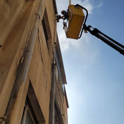 אדם במנוף צהוב עובד על גג בניין