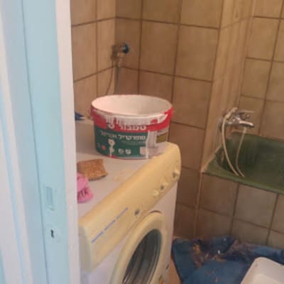 דלי צבע על מכונת כביסה בחדר אמבטיה
