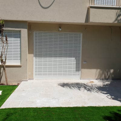 תריסי אלומיניום לבנים על חלונות ודלת