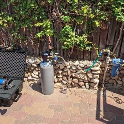 מיכל גז, צינור ומד לחץ ליד גדר עץ