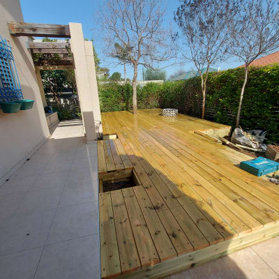 דק עץ עם כלים ועציצים בגינה