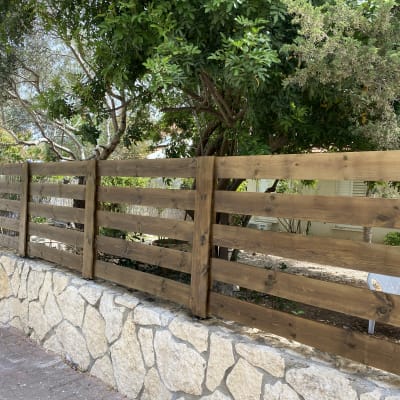 גדר עץ חומה על קיר אבן בגינה