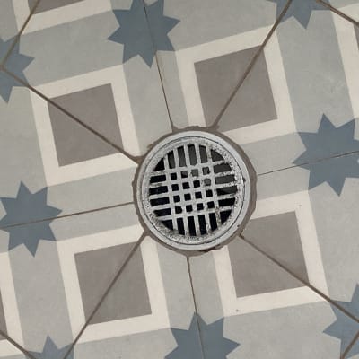 רצפת אריחים עם פתח ניקוז עגול במרכז