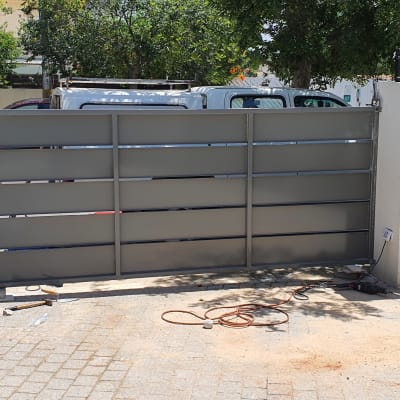 שער מתכת אפור עם מסגרת, חוטים וכלים על הקרקע