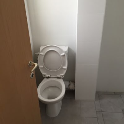 Toilet in a partially renovated bathroom with tiled floor.