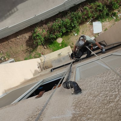 אדם עם ציוד טיפוס ליד צינור על קיר חיצוני