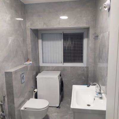 חדר אמבטיה משופץ עם כיור, אסלה ומכונת כביסה