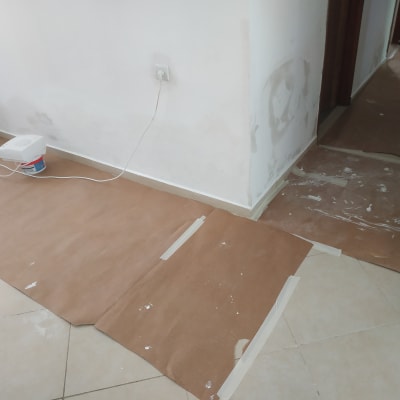 נייר חום על הרצפה, דלי צבע, קיר צבוע חלקית