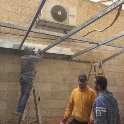 עובד על סולם מתקין קורות מתכת לבנייה