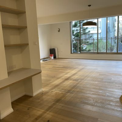 דלי אדום ומגב על רצפת עץ בחדר ריק