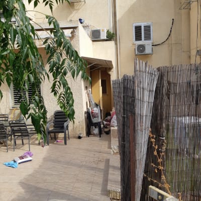 מרפסת עם כיסאות פלסטיק, מזגנים על הקיר, גדר במבוק