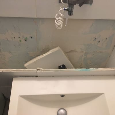 כיור שבור עם קיר מתקלף וברז חשוף