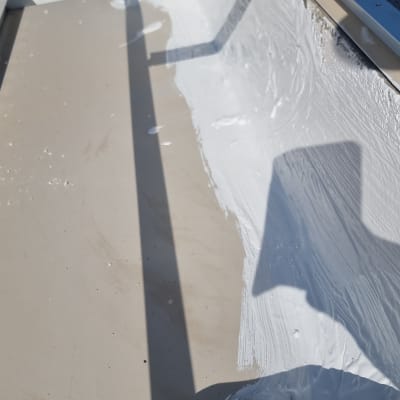 מריחת חומר איטום לבן על משטח מתכת