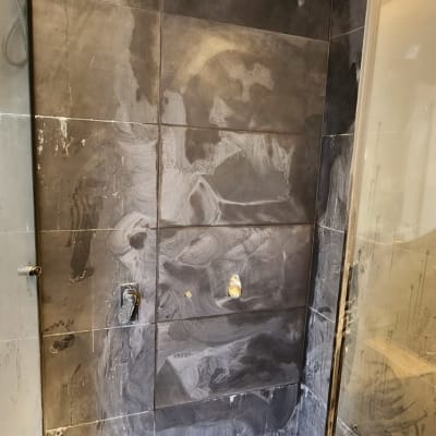 שיפוץ מקלחת עם אריחים כהים, צינור מים חשוף