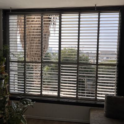 תריסים אופקיים על חלון גדול עם נוף חיצוני