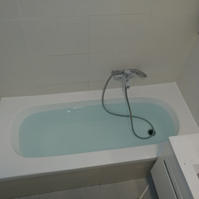 אמבטיה עם מים וברז מקלחת על קיר אריחים