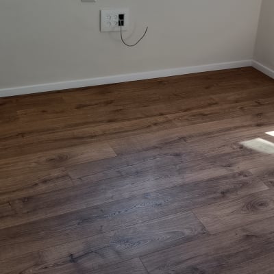 רצפת פרקט עץ כהה בחדר ריק עם אור שמש