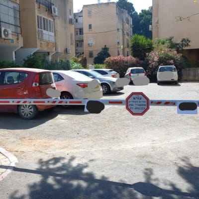 שער חשמלי חוסם כניסה לחניון עם שלט אזהרה